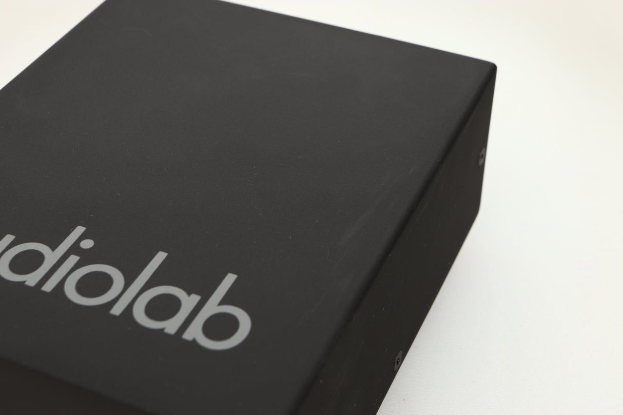 Close up view of a used Audiolab DC Block Mains Filter in Black finish showing light scratching on the top