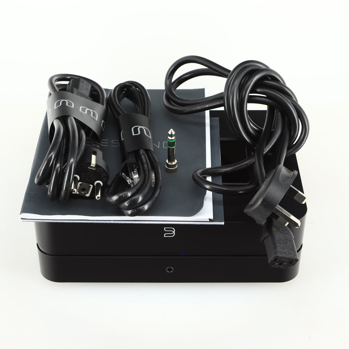 Top view of a used Bluesound Power Node Streamer in a black finish showing mains cable, manual, 2x schuko cables and adaptor