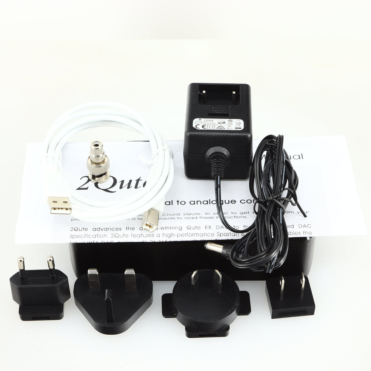 Top of a used Chord electronics 2Qute Chordette Digital Analogue Converter in a black finish showing Manual, Power Supply, USB Cable, BNC Adaptor, Mains Plug and Schuko Plugs