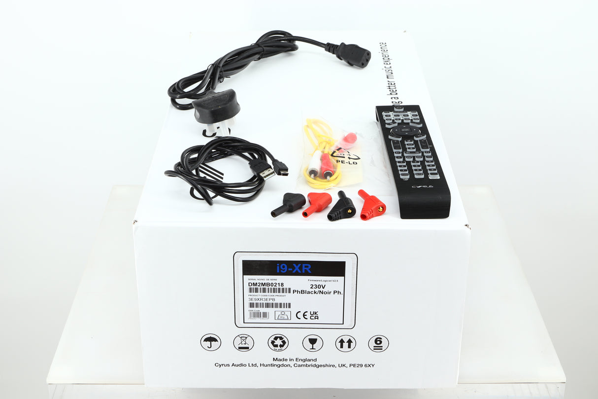 Box of a used Cyrus i9-XR Integrated Amplifier in PhBlack finish showing mains cable, remote, USB cable, MC-Bus cable, and speaker plugs