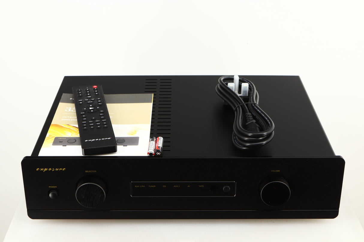 Top of a used Exposure 3510 Integrated Amplifier in a black finish showing Remote, Mains Cable, 2x Batteries and Manual
