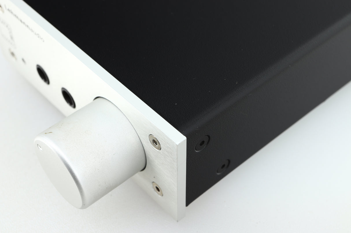 Close up of a used Lehmann Black Cube Linear Headphone Amplifier in a silver finish showing some marking on knob on fascia