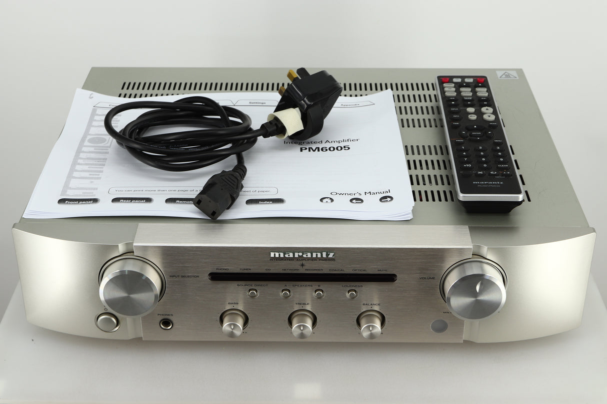 Accessories of a used Marantz PM6005 Integrated Amplifier in silver finish showing manual, mains cable, and remote