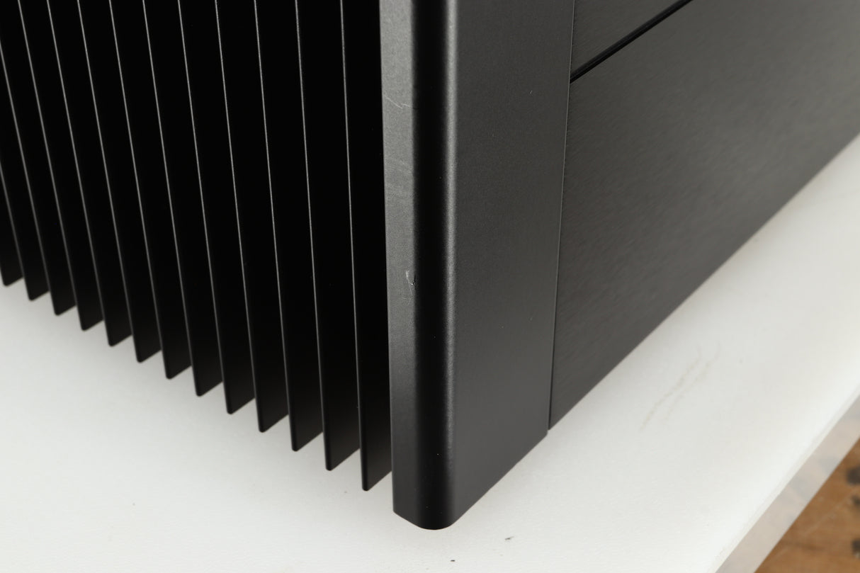 Close up of a used Meridian 557 Power Amplifier in a black finish showing a small scratch on front left corner