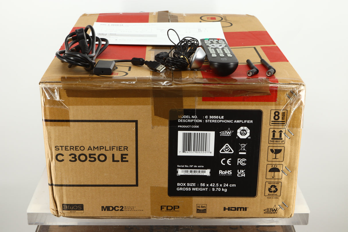 View of the box of a used NAD C3050 LE Integrated Amplifier showing accessories, mains cable, remote, manual, setup mic, and 2 bluetooth/WiFi antenna