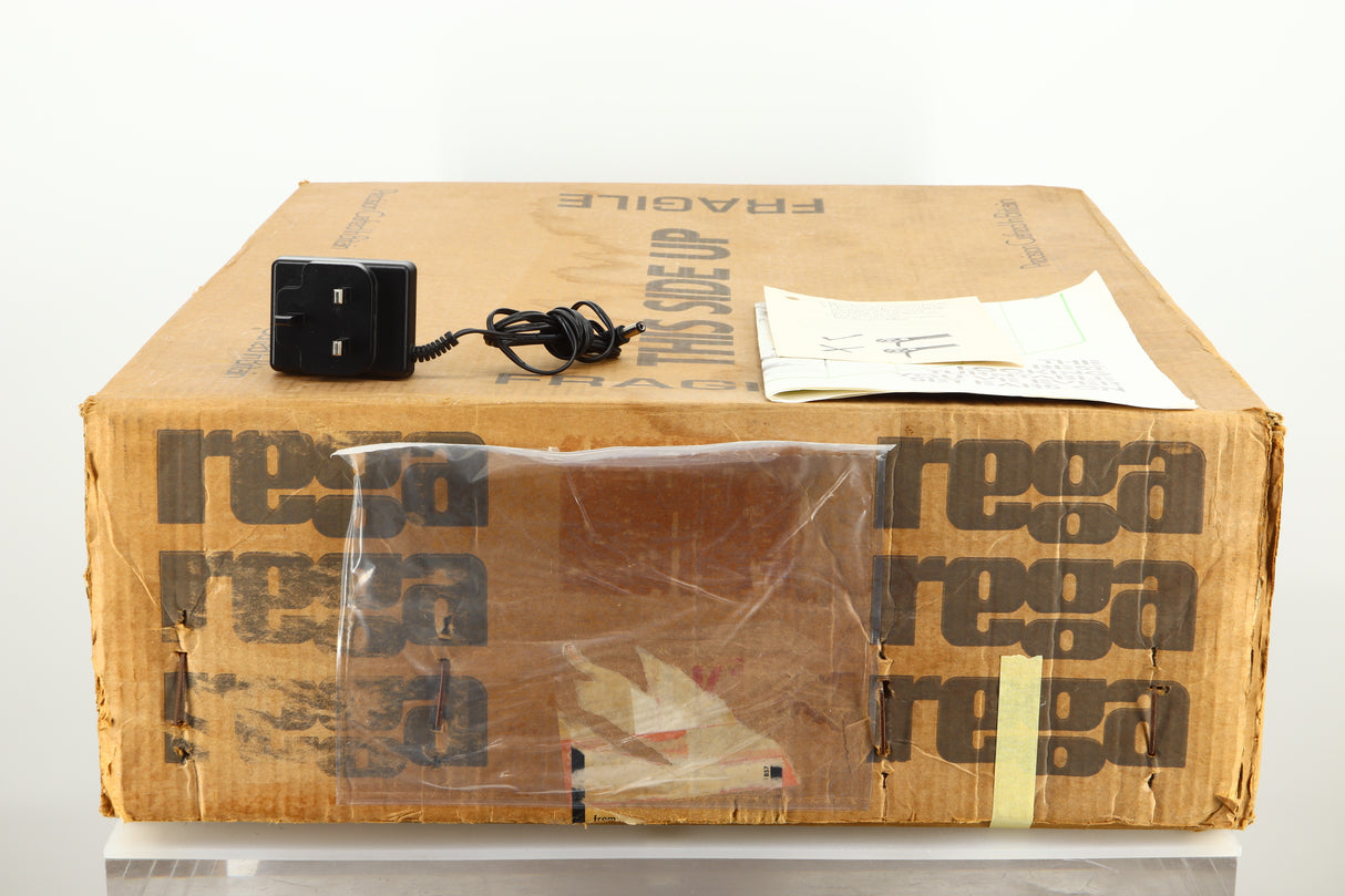 Box of a used Rega Planar 2 Turntable / 24V Upgraded / Exact Cartridge showing a power supply, manual and cartridge alignment protractor