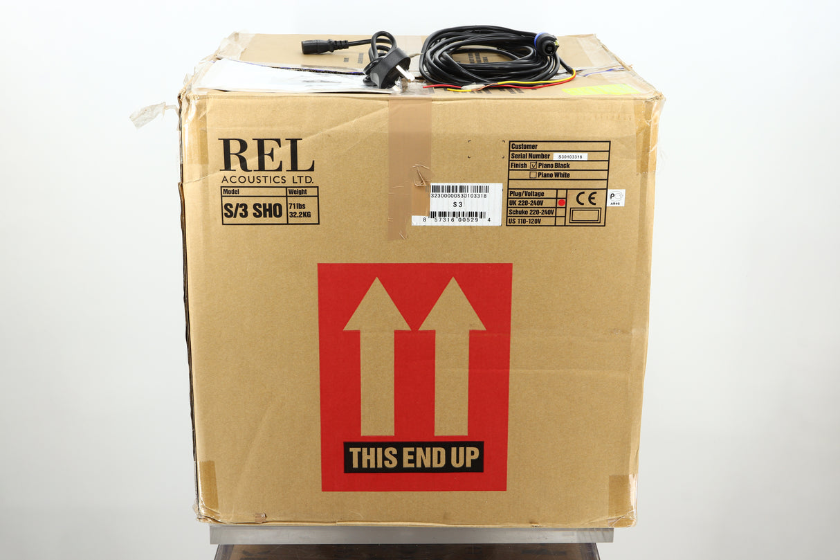 Box of a used REL S/3 SHO Subwoofer in Piano Black finish showing mains cable, manual, and hi-level cable