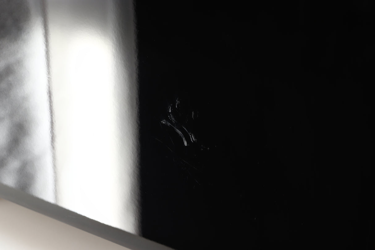 Close up view of a used REL T9X Subwoofer in Piano Black finish showing scratches on the left side
