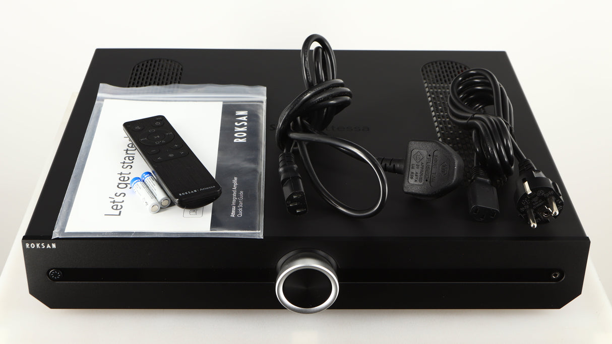 Top of a used Roksan Attessa Integrated Amplifier in a black finish showing Manual, Remote, 2x Batteries, Mains Cable and Schuko Cable