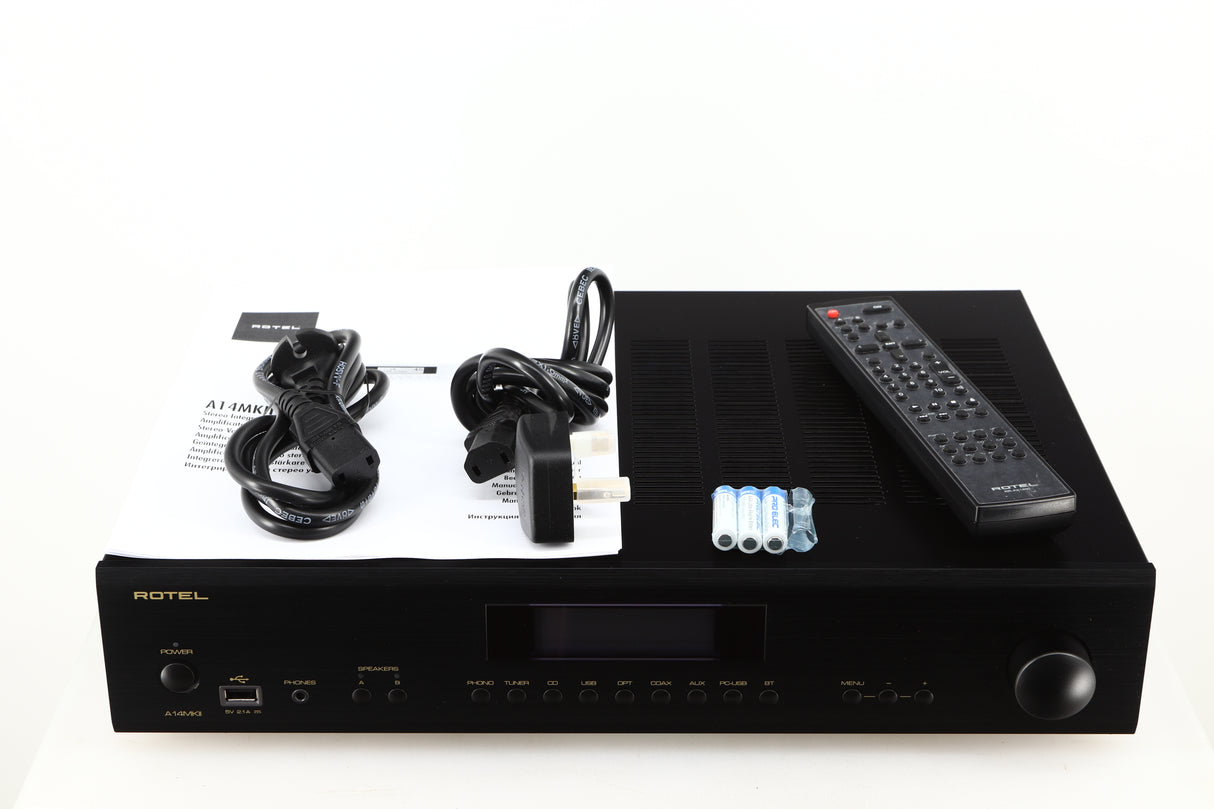 Top of a used Rotel A14 MKII Integrated Amplifier in a black finish showing Mains Cable, Batteries, Remote, Schuko Cable and Manual