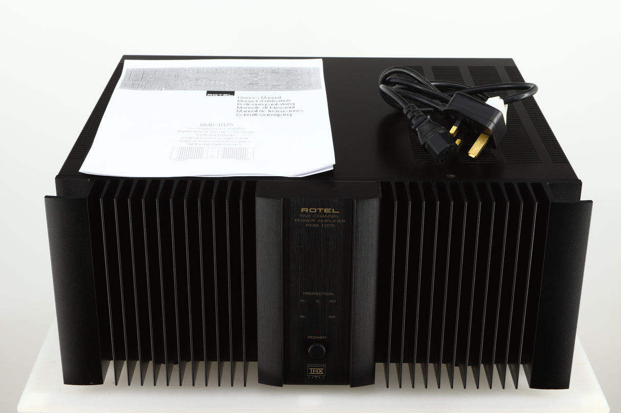 Top view of a used Rotel RMB1075 Power Amplifier in a black finish showing a manual and a mains cable