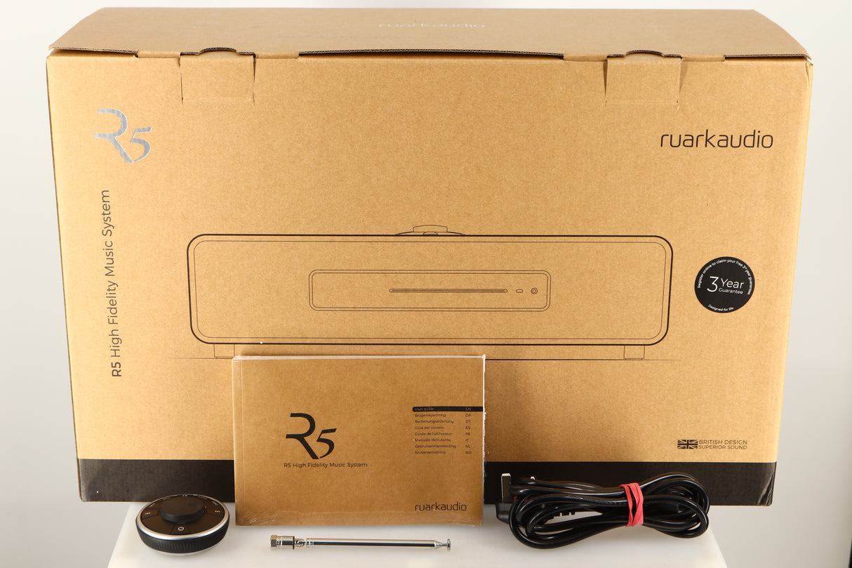 Box of a used Ruark R5 Music System in Walnut finish with mains cable, manual, remote, and aerial