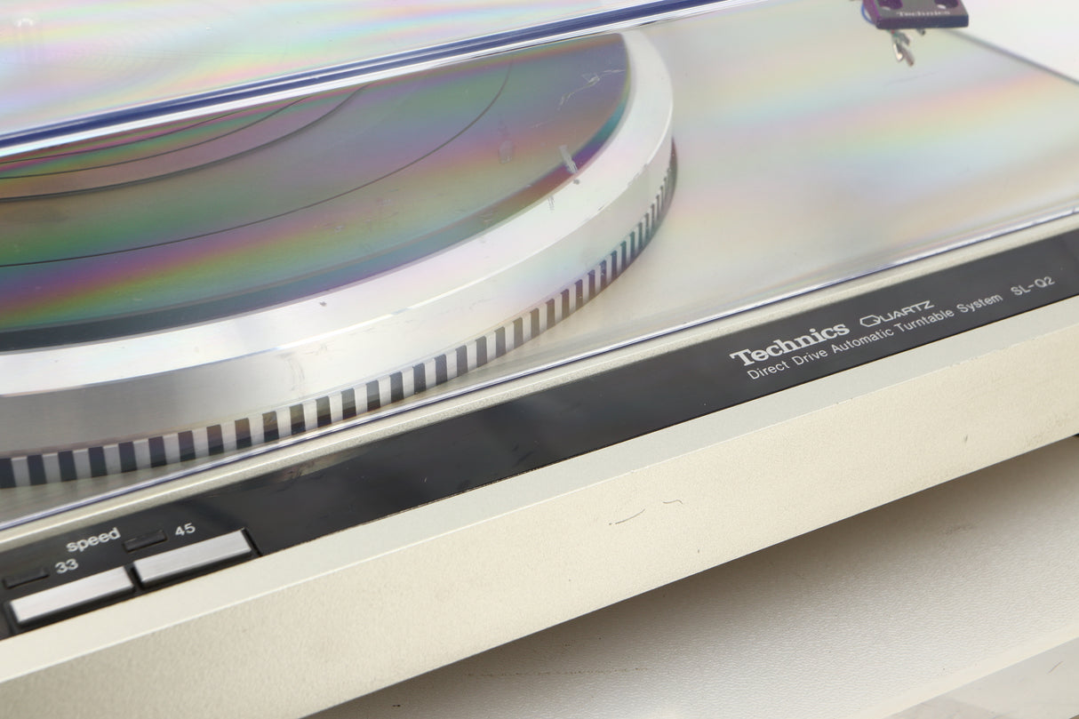 Close up view of a used Technics SL-Q2 Direct Driver Turntable in Silver showing some scratching on the turntable and the lid