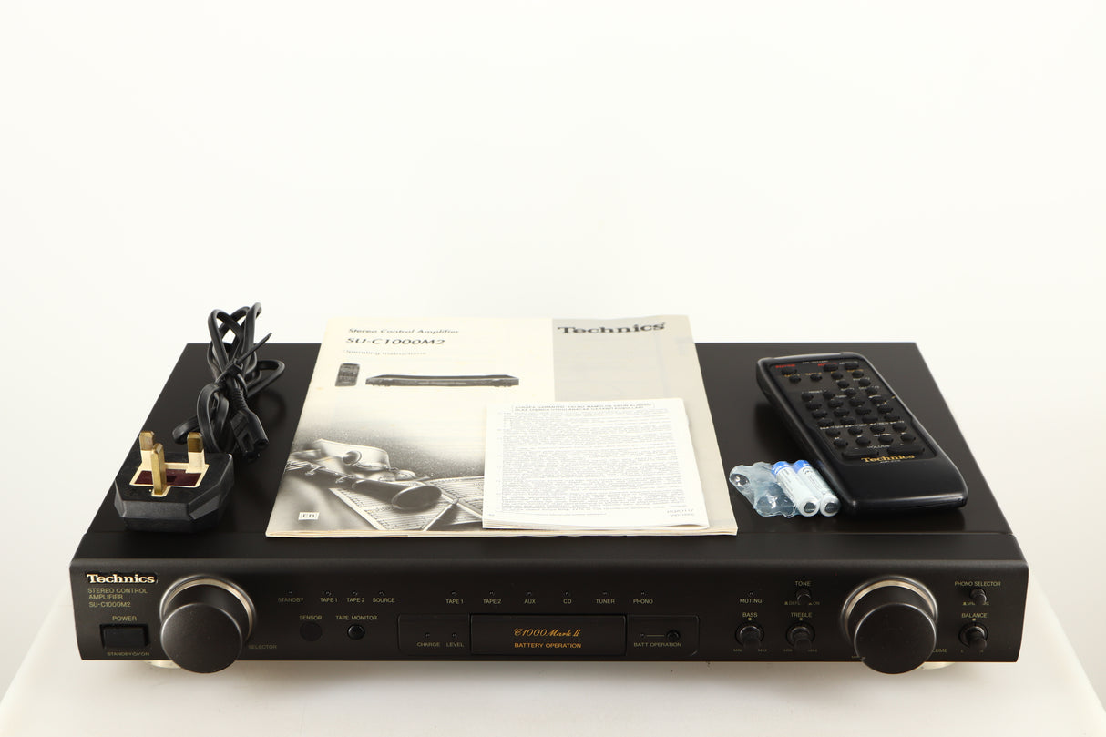 Top of a used Technics SU-C1000M2 Pre Amplifier in a black finish showing Power Cable, Manual, Remote and Batteries