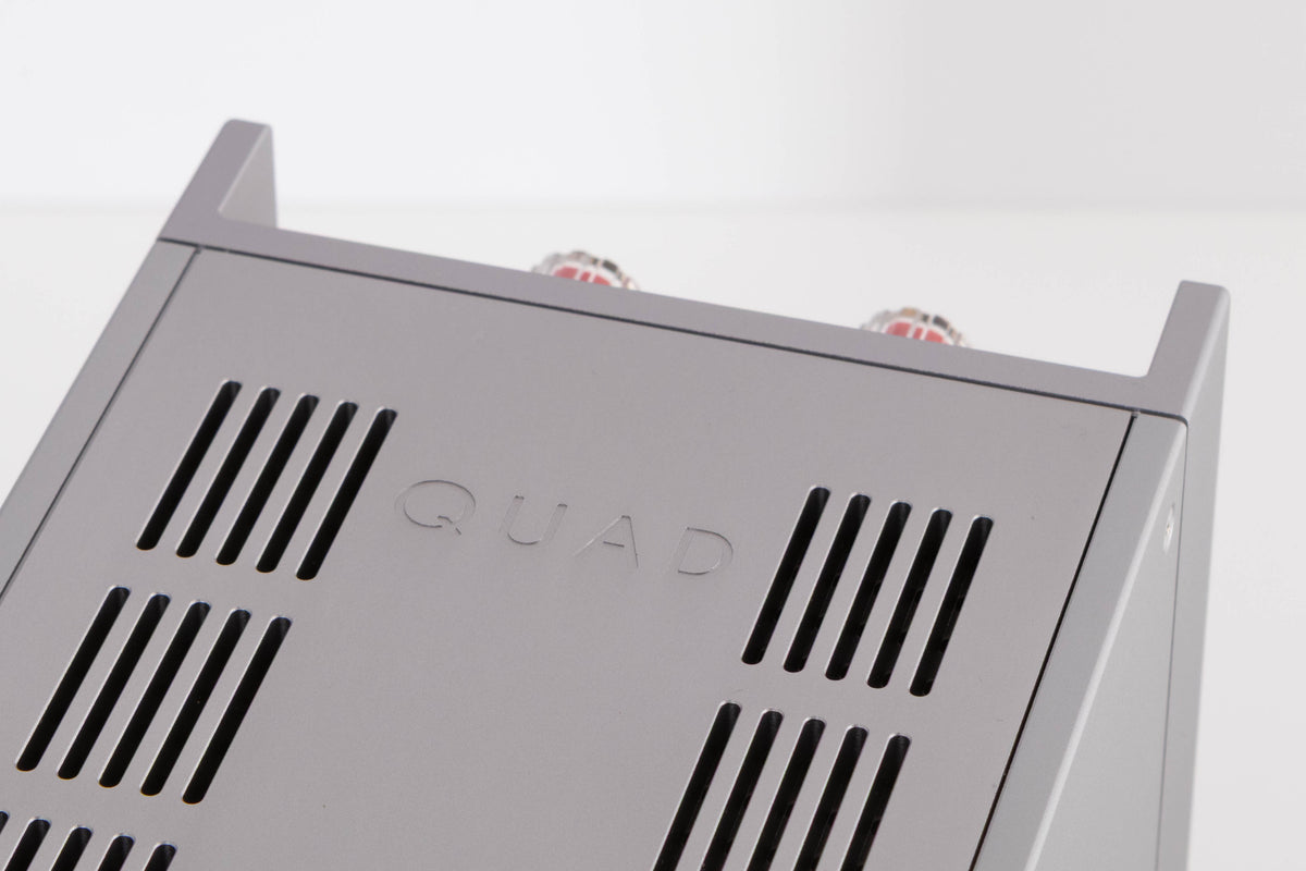 Close up of a used Quad 303 Power Amplifier in a Silver finish showing logo on top