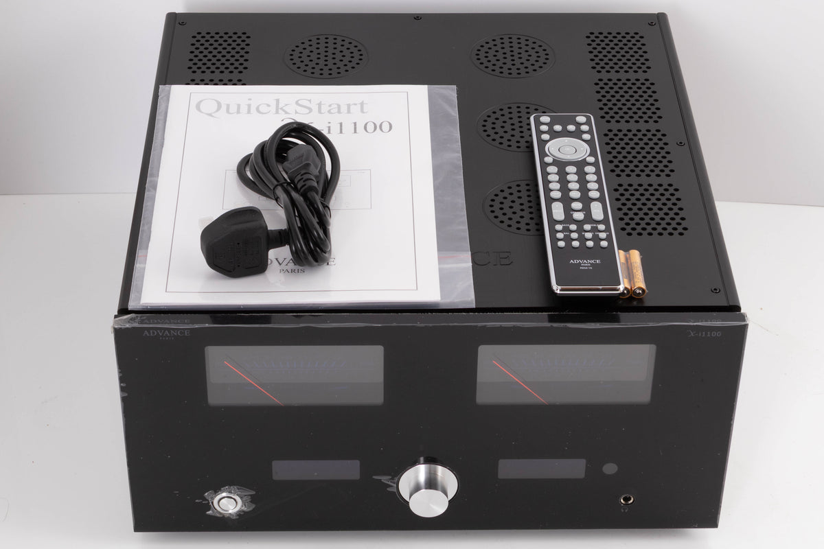 Top of a used Advanced Paris X-i1100 Integrated Amplifier in a Black finish showing Manual, Mains Cable, Remote and Batteries