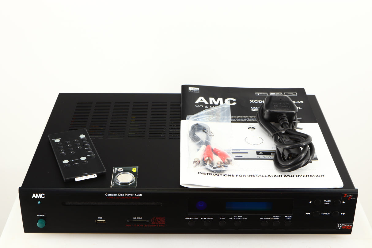 Top of a used AMC XCDise-vt CD Player With MD5404us2 Tube Output in a black finish showing Remote, Battery, Interconnect Cable, Mains Cable and Manual