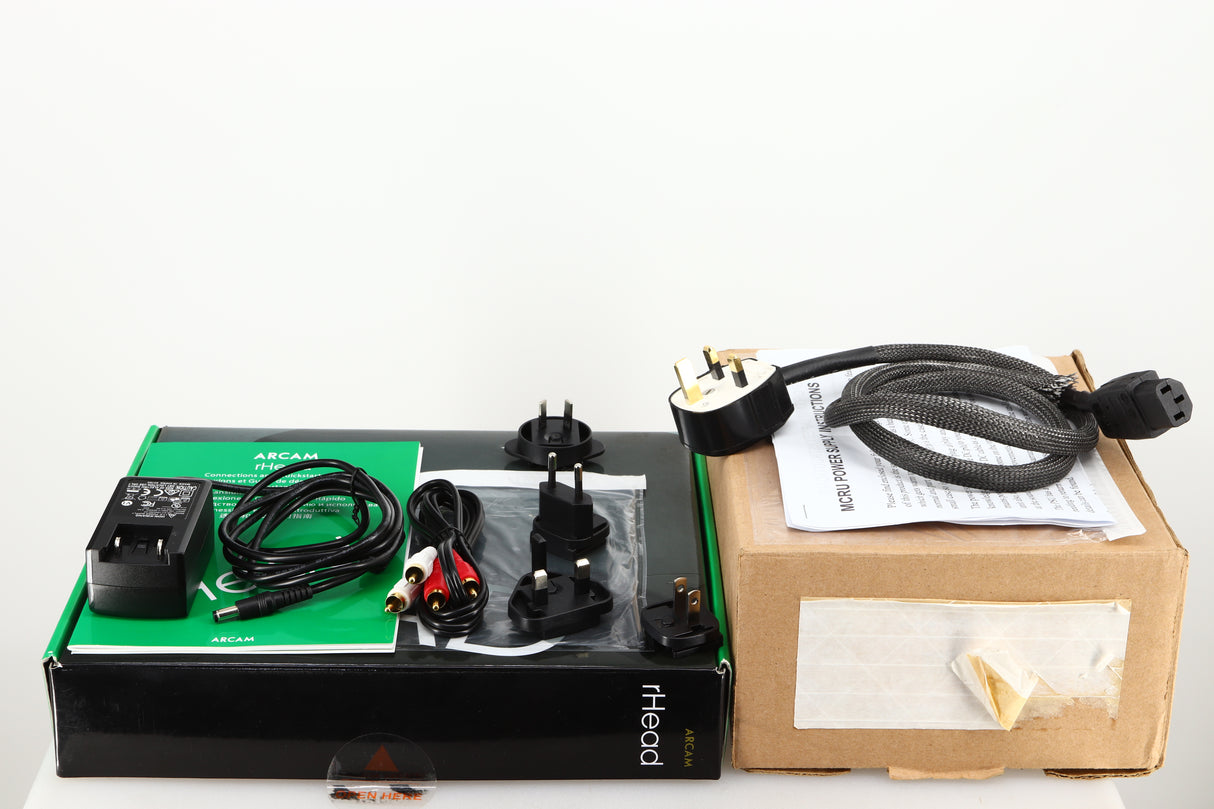 Box for a used Arcam rHead Headphone Amplifier W/ MCRU Power Supply showing Power Supply, Interconnect Cable, Manuals, Mains Plug, Schuko Plugs and Power Cable 