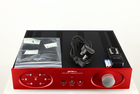 Top of a used Astin Trew AT2-2100 Integrated Amplifier in a red finish showing Mains Cable, Remote, 2x Batteries and Manual