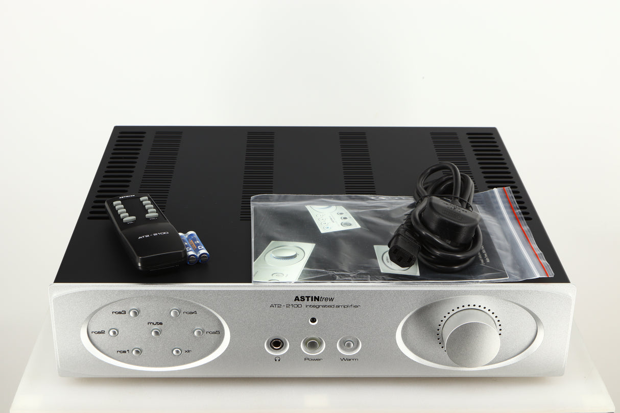 Top of a used Astin Trew AT2-2100 Integrated Amplifier in a silver finish showing Remote, 2x Batteries, Manual and Mains Cable 