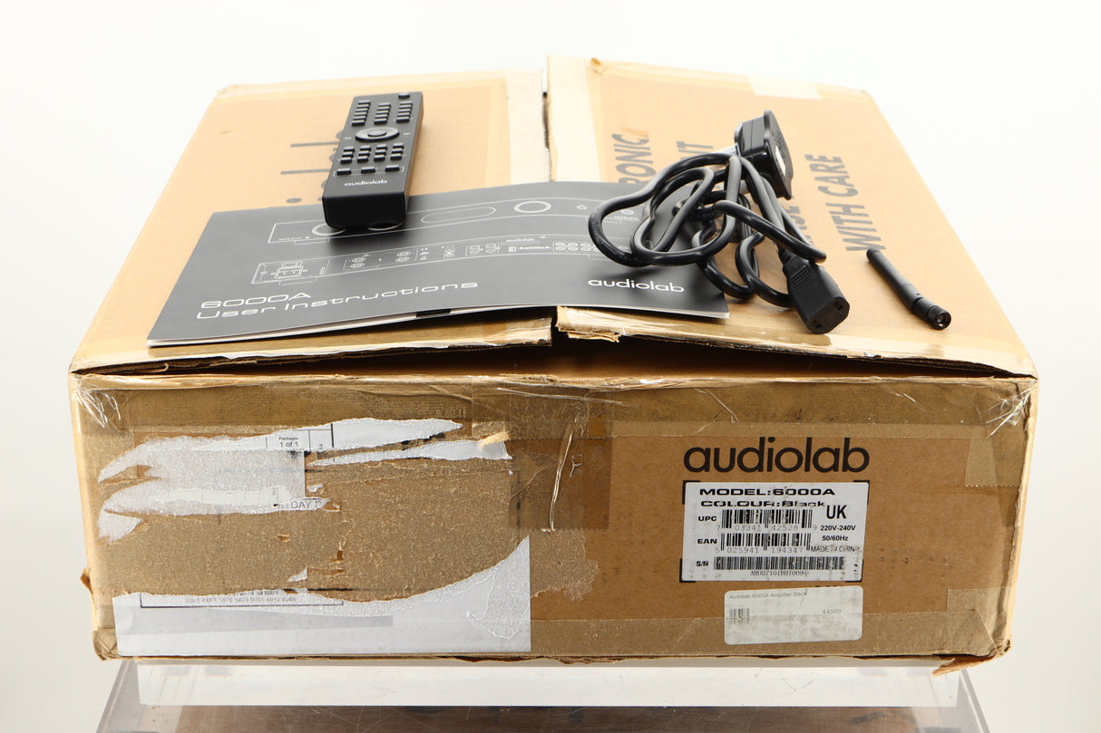 Box of a used Audiolab 6000A Integrated Amplifier in Black finish showing mains cable, manual, remote, and antenna