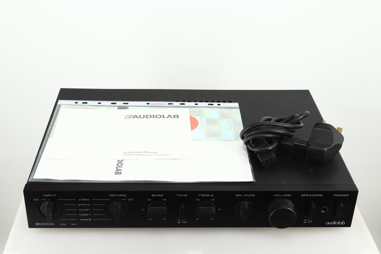 Top of a used Audiolab 8000A Integrated Amplifier in a black finish showing a manual and mains cable 