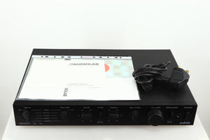 Top of a used Audiolab 8000A Integrated Amplifier in a black finish showing a manual and mains cable 