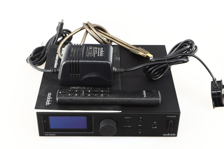 Top of a used Audiolab M-DAC Digital Analogue Converter in a black finish showing Remote, PSU, Manual and USB Cable