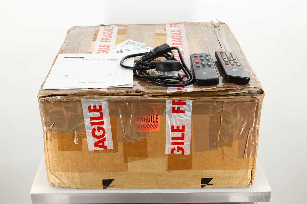 Box of a used Ayre CX-7 CD Player in silver finish showing manual, mains cable, and remotes