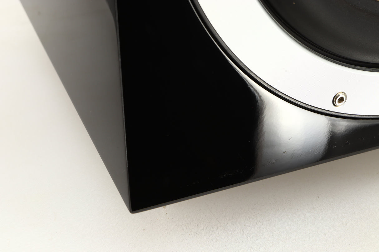 Close up of a used B&W ASW10CM Subwoofer in a gloss black finish showing scratching on fascia