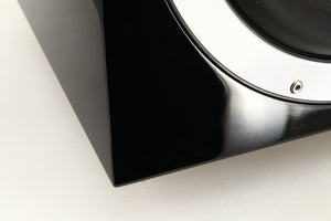 Close up of a used B&W ASW10CM Subwoofer in a gloss black finish showing scratching on fascia