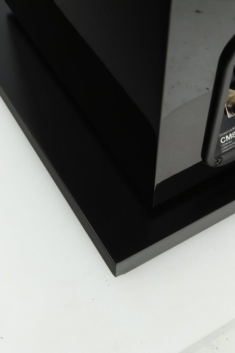 Close up of a used B&W CM8 S2 Floorstanding Speaker in a piano black finish showing some damage on the base