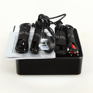 Top of a used Bluesound Node Icon Streamer in a black finish showing Manual, Warranty Card, Power Cable, Interconnect Cable, Ethernet Cable and Schuko Power Cable