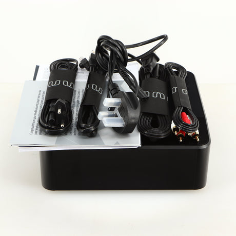 Top of a used Bluesound Node Icon Streamer in a black finish showing Manual, Warranty Card, Power Cable, Interconnect Cable, Ethernet Cable and Schuko Power Cable