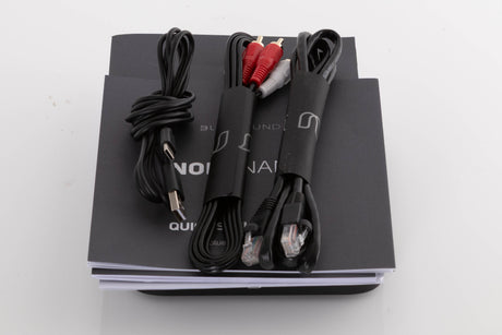 Top of a used Bluesound Node Nano Streamer in a Black finish showing Manual, USB Cable, Ethernet Cable and Interconnect Cable