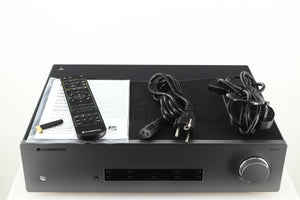 Top of a used Cambridge Audio CXA81 GEN2 Integrated Amplifier in a lunar grey finish showing Remote, Bluetooth Antenna, Mains Cable, Schuko Cable and Manual