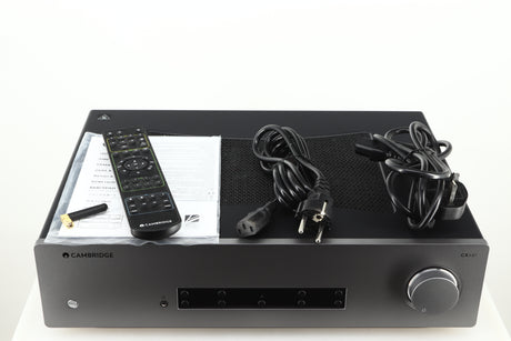 Top of a used Cambridge Audio CXA81 GEN2 Integrated Amplifier in a lunar grey finish showing Remote, Bluetooth Antenna, Mains Cable, Schuko Cable and Manual
