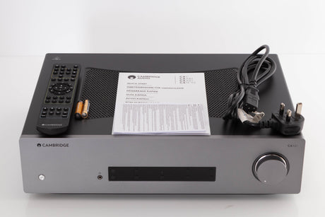 Top of a used Cambridge Audio CXA81 Integrated Amplifier in a Lunar Grey finish showing Remote, Batteries, Manual and Mains Cable