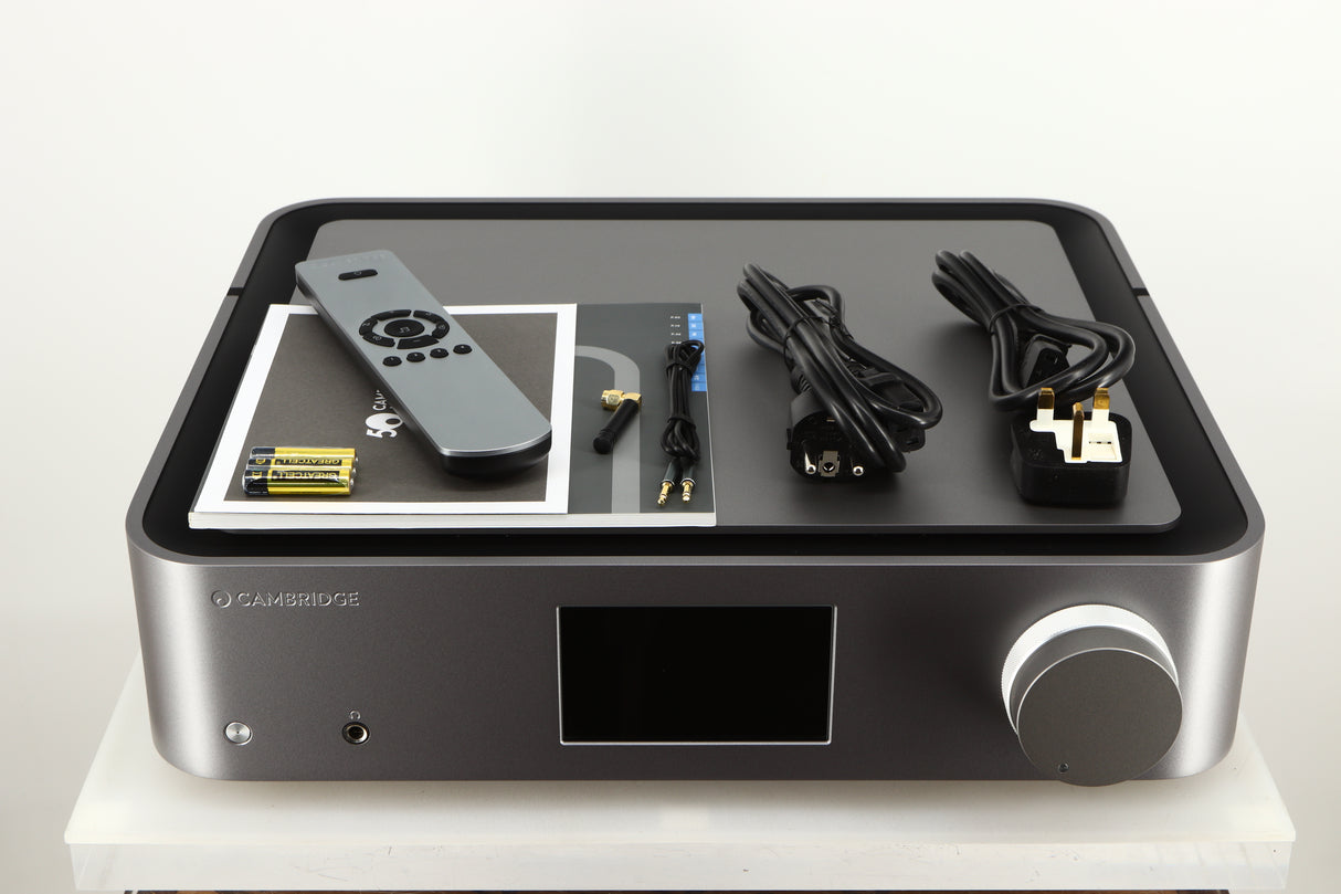 Top of a used Cambridge Audio Edge NQ Network Pre Amplifier in a grey finish showing Manual, Warranty Card, Remote, 3x Batteries, Mains Cable, Schuko Cable, Bluetooth Cable, AUX Cable