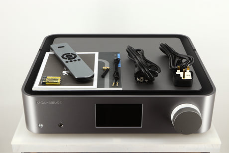 Top of a used Cambridge Audio Edge NQ Network Pre Amplifier in a grey finish showing Manual, Warranty Card, Remote, 3x Batteries, Mains Cable, Schuko Cable, Bluetooth Cable, AUX Cable