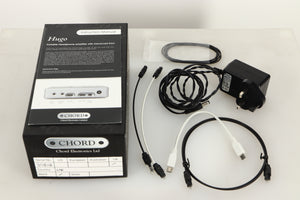 Box of a used Chord Electronics Hugo DAC / Headphone Amplifier in Black finish with mains cable, manual, 3x optical cables, USB cable, and rubber bands 