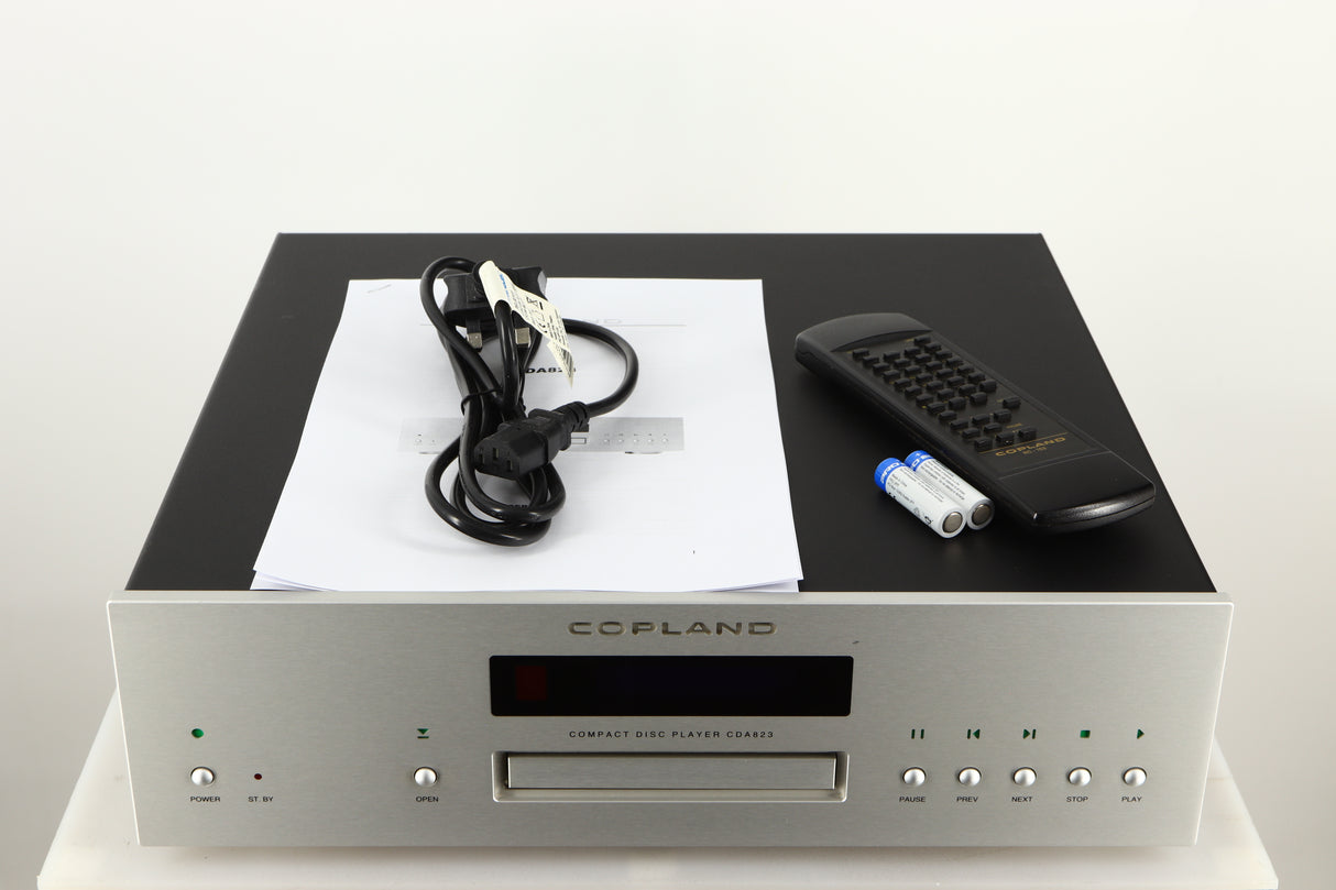 Top of a used Copland CDA823 CD Player in a silver finish showing Manual, Remote, 2x Batteries and Mains Cable
