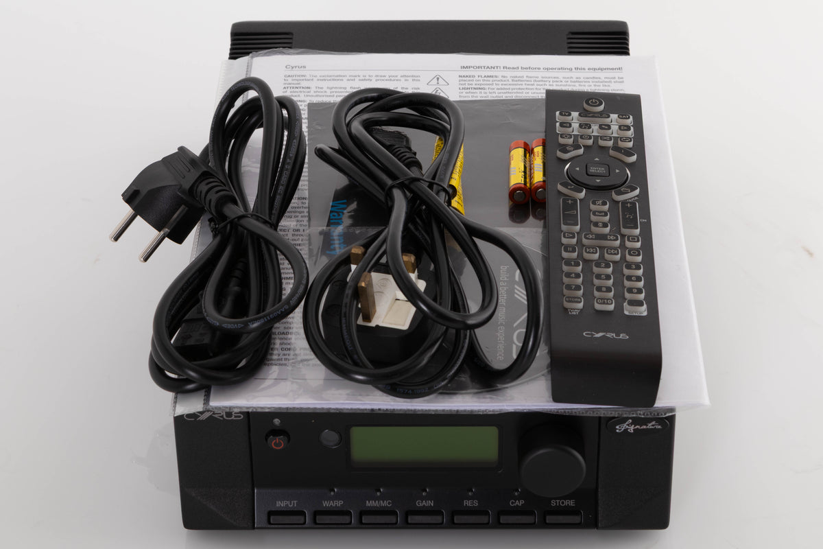 Top of a used Cyrus Phono Signature Phonostage in a Brushed Black finish showing Remote, Batteries, Manual, Mains Cable and Schuko Cable