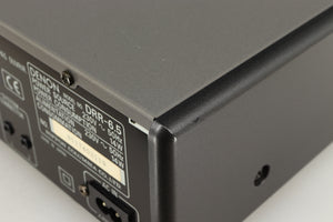 Close up of a used Denon DDR-6.5 Cassette Deck in a silver finish showing some scratches on rear left corner
