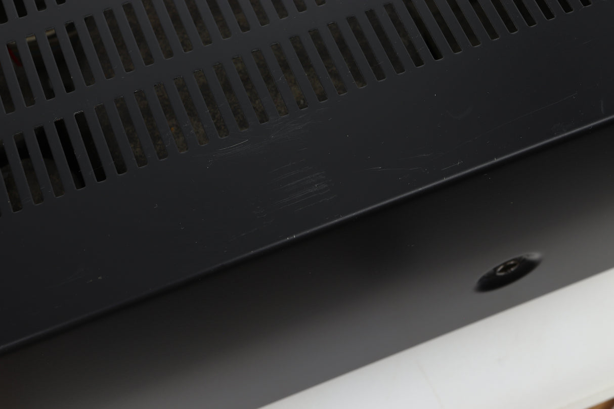 Close up view of a used Denon PMA-720 Integrated Amplifier in Black finish showing scratches on the top near the left side 