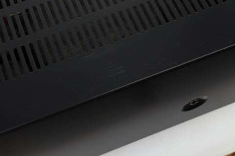 Close up view of a used Denon PMA-720 Integrated Amplifier in Black finish showing scratches on the top near the left side 