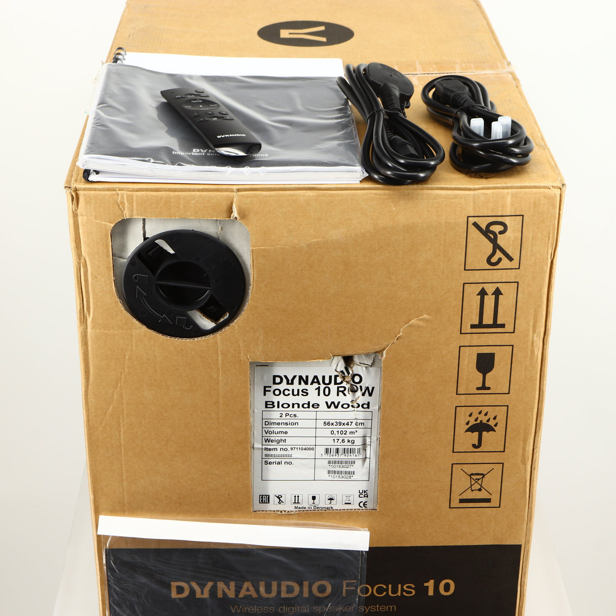 Box for a used Dynaudio Focus 10 Standmount Speaker in a blonde finish showing 2x Manuals, 2x Mains Cables, Remote and 2x Grilles