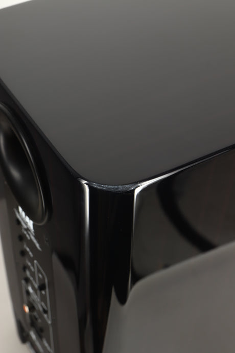 Close up view of a used ELAC Navis B51 Active Standmount Speaker in Gloss Ebony Emara finish showing marks under the top coat
