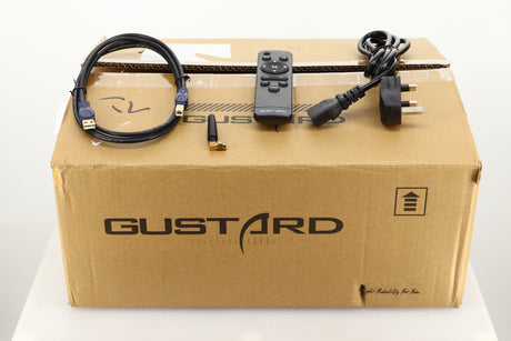 Box of a used Gustard R26 Discrete R2R DAC in Black finish showing mains cable, remote, USB cable, and Bluetooth antenna