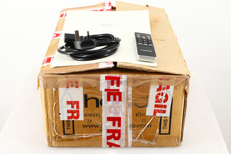Box of a used Heed Abacus DAC in Black finish showing mains cable, manual, and remote 